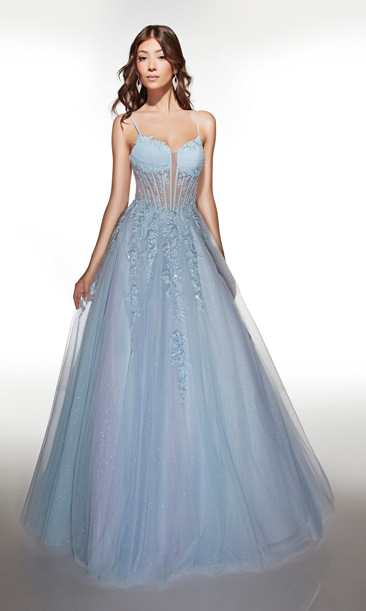 A woman wears the Alyce 62061 long prom dress, featuring light blue tulle, a sleeveless lace corset bodice with floral appliqués, thin straps, and a full ballgown skirt against a plain white background.